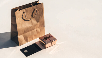 Brown paper bag, wrapped gift box, and credit card are arranged on light surface, evoking shopping theme. scene suggests minimalist and eco friendly approach to gift giving