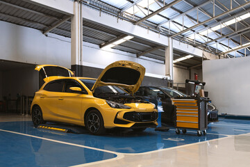 Yellow car with open hood in a professional auto service center.