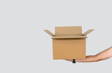 Hand Holding Open Cardboard Box Isolated on Light Gray Background with Copy Space