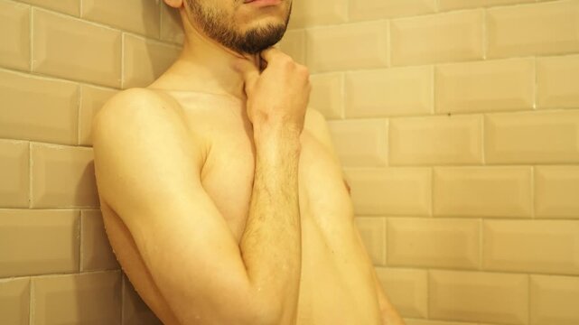 An attractive thin man washes in the shower