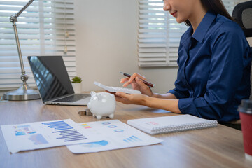Fototapeta premium Asian business professionals analyze accounts and documents, calculate budgets, expenses, loans, mortgages, insurance, real estate investments, and manage income, taxes, and residential strategies