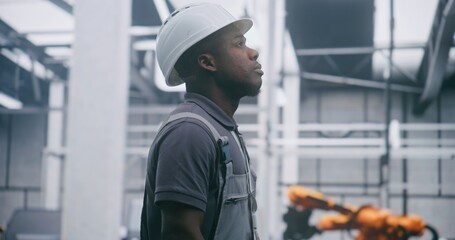 Obraz premium Focused Factory Engineer Provides Professional Monitoring Industrial Systems in Safety Hard Hat and Overalls With Serious Expression. Concept Responsibility For Monitoring Complex Industrial Systems.