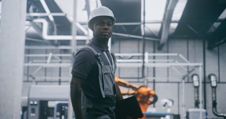 Professional Plant Manager Moving Through Industrial Workshop With Tablet in Hand, Reviewing Production Systems, Supervising Robotic Assembly Lines and Ensuring Efficiency in Modern Smart Factory.