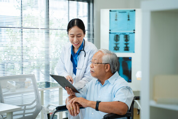 Asian female doctor in white coat consulting with senior male patient in the clinic.Healthcare professional using tablet to discuss medical results or treatment options.older elderly health care