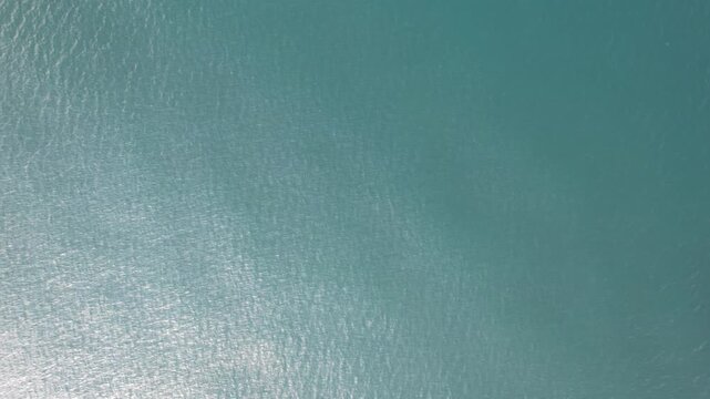 Aerial drone flight over the calm surface of the Black Sea with sunlight reflecting on deep blue water.