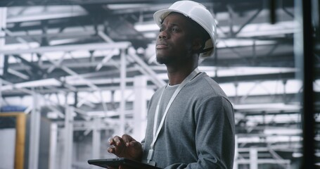 Dedicated Technician Concerned Expression While Holding Tablet, Suggesting Troubleshooting Industrial Alert or Issue in Large, Modern Machinery of Plant. Problem solving and Operational Intensity.