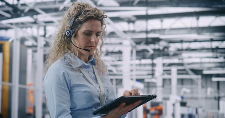 Focused Female Technical Specialist Conducting Digital Diagnostics in Industry 4.0 Facility. Woman Uses Tablet For Complex Data Analysis While Wearing Hands Free Headset. Mobile Data Processing.