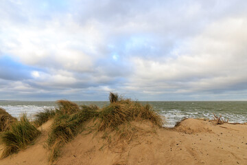 Dramatische K&uuml;stenlandschaft mit Sandd&uuml;nen und wechselhaftem Himmel