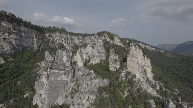 Aerial drone shot gliding past the Sairme Pillars in Lechkhumi, Georgia, revealing towering rock formations surrounded by green hills and untouched Caucasus nature. High-quality 4K footage.