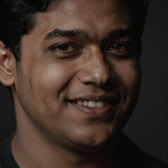 Obraz premium Close-up Portrait of a Joyful South Asian Man with Dramatic Lighting and Realistic Skin Texture