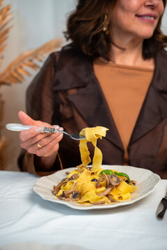Close up of woman lifting fresh Italian pasta with fork during elegant home dinner