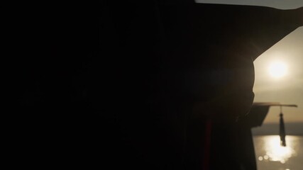 Close-up of a graduation cap with tassel in silhouette against sunset and lake reflection, symbolizing success, calm, and new beginnings.