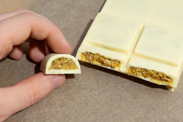 Close-up of white Dubai-style chocolate with pistachio filling, one piece broken to reveal the rich...