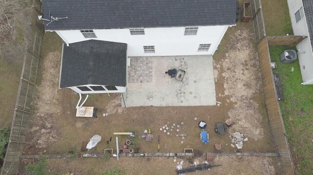 Overhead drone shots of man working on his backyard paver patio doing a DIY construction project. 