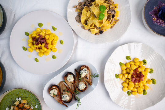 Italian Gourmet Dishes Flat Lay with Gnocchi, Fresh Pasta and Appetizers on White Tablecloth
