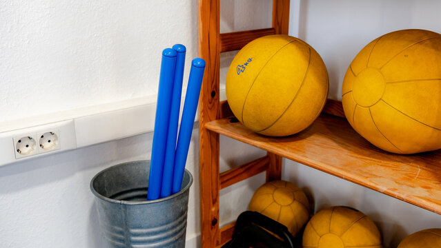 Gym equipment arranged on wooden shelf and in metal bin