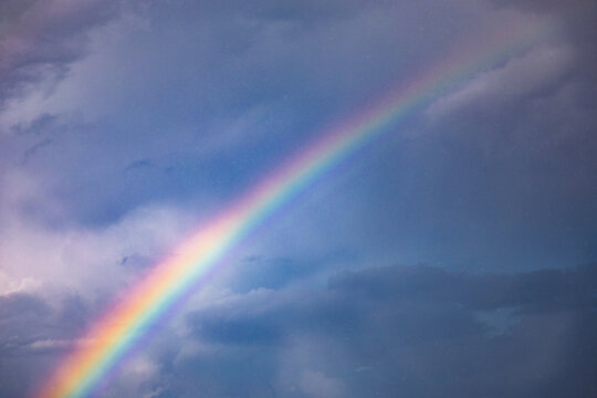 Vibrant rainbow arcs through a cloudy sky