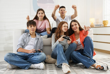 Happy teenagers playing video game together at home