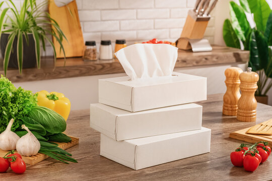 Three white boxes with paper napkins are stacked on top of each other on a cozy kitchen table next to tomatoes, peppers, and lettuce. Horizontal photo. Layout.