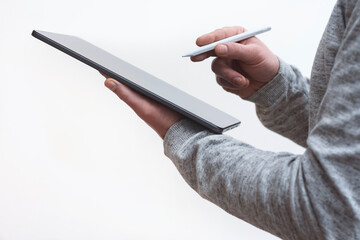 Close up of man holding digital tablet in one hand and stylus pen in the other against clean white background. Concept for technology, design and productivity work.