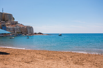 Wide coastal view with sandy beach in Montenegro, calm sea, and seaside town. Urban shoreline, leisure travel, and balanced coexistence of city life and nature.