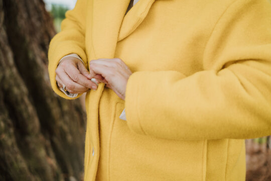 Buttoning a yellow coat for warmth and style