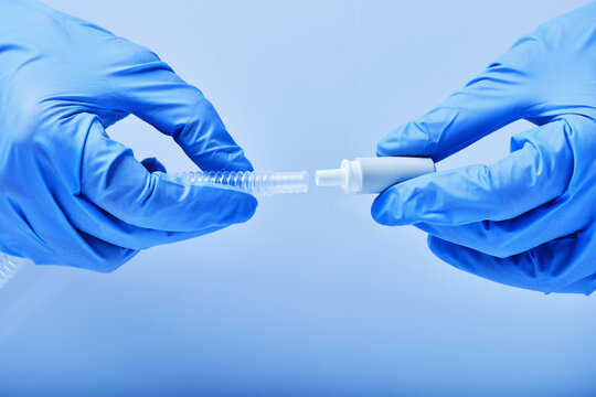 hands in blue gloves connect the tip of the catheter - Powered by Adobe