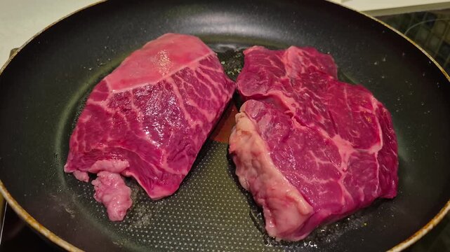 Close-up of beef steaks being cooked in a frying pan
