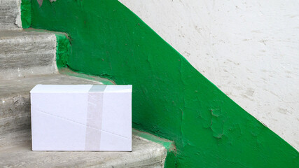 white shipping box located on gray steps inside a staircase area