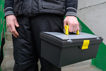 worker carrying a black professional toolbox in a residential building entrance