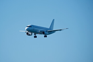 Fototapeta premium White Commercial Airplane Approaching for Landing Against Clear Blue Sky, Side View.