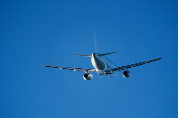 Fototapeta premium Commercial Airplane Departing After Takeoff, Rear View in Blue Sky. Passenger Airliner Flying Away on Departure, Back View