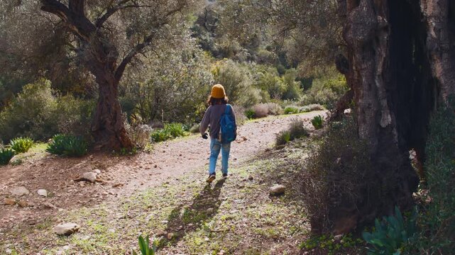 A child walks and puts on a backpack. Adventures and travel. A boy with a backpack walks along a mountain trail. Back view. Trips and vacations with children.