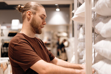 Young man selecting a pillow in a home goods store, testing softness.