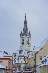 Fototapeta premium view of frozen downhill street with snow on roofs and main tower on top on cloudy winter day white landscape