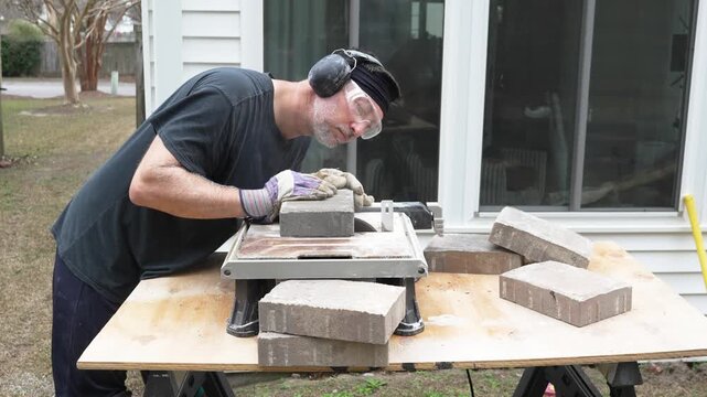 Man working on his home DIY project building a paver patio in his back yard
