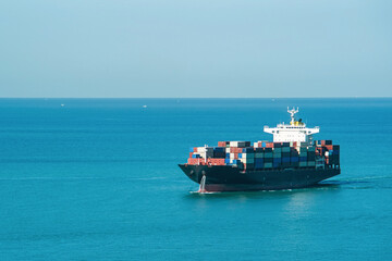 large commercial container ship carrying colorful cargo containers at a deep sea. International maritime trade and global logistics business.