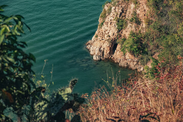 Rocky cliff surrounded by clear blue sea and coastal scenery. Natural landscape representing travel, adventure, nature and seaside environment.