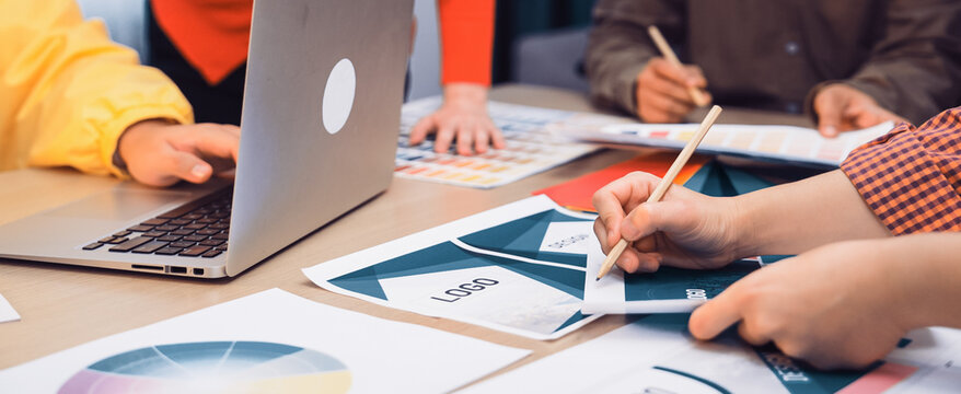 A dynamic team of creative professionals collaborates in a modern office space, analyzing marketing strategies and discussing design elements with various tools and documents. SACTR - Powered by Adobe