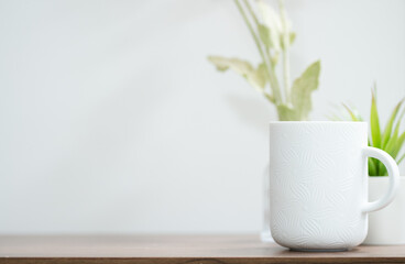 White ceramic cup and green plants in the background with copy space