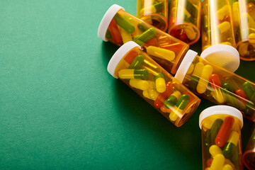 Pills in orange plastic bottles on a green table.
