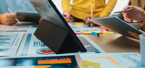 A vibrant scene of professionals engaged in a collaborative business meeting, utilizing digital devices and analytics reports on the table for strategic planning and discussions. SACTR