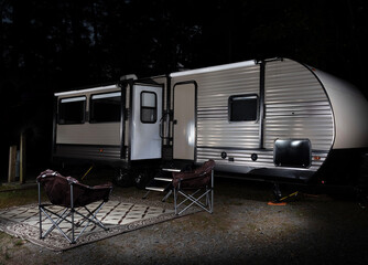 Headlights shining on a dark travel trailer at night