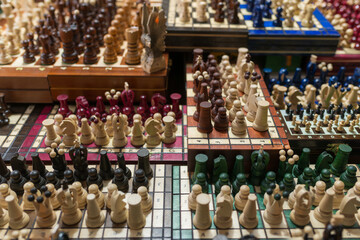 Close-up of many wooden chess pieces set on different boards in vibrant colors. A rich background for strategy, competition, thinking, and classic board game culture with strong texture and depth of f © Volha
