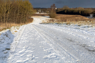 Frozen rural road in winter daylight landscape.