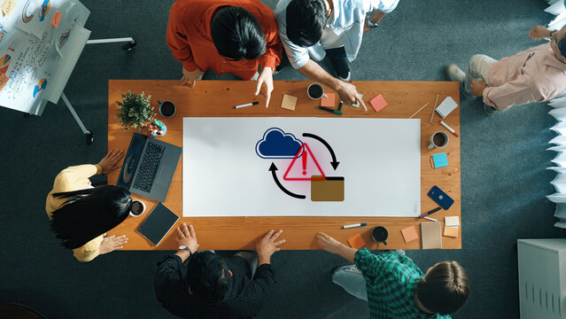 A diverse group of professionals engages in a team meeting focused on cloud technology, analyzing diagrams and sharing ideas in a collaborative workspace. Gantry - Powered by Adobe