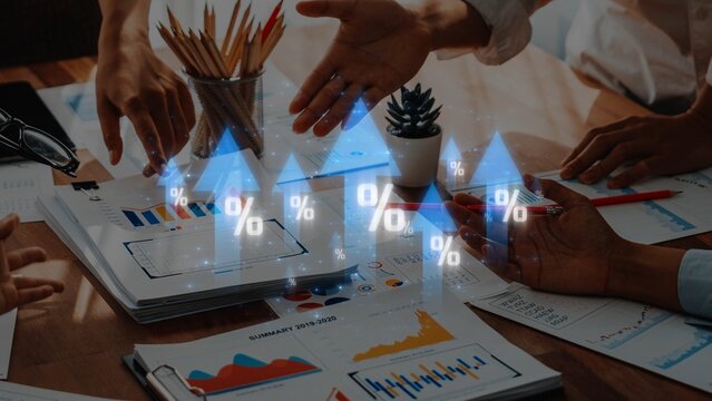A diverse business team engages in data analysis, examining growth charts and digital percentage icons during a brainstorming session in an office setting. Raster