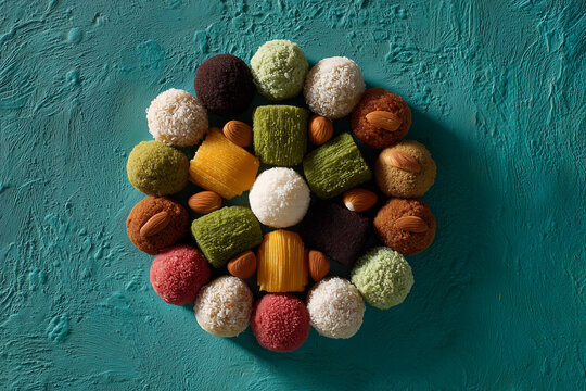 Artistic mandala arrangement of revdi sweets on teal background.