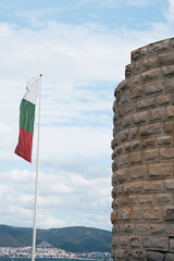 national flag of Bulgaria flying near an old stone fortification of Nessebar overlooking the scenic landscape. This location is popular for sightseeing and cultural appreciation
