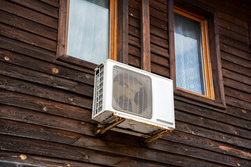Workers fit an air conditioning unit on the exterior of a wooden house in Bulgaria. This is a common activity during summer in the region to ensure indoor comfort